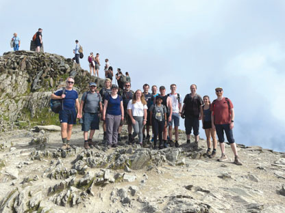 Volunteers in hiking garb standing atop mountain