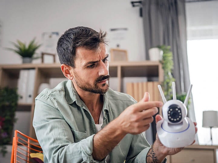 Adult male with facial hair looking at the back of a cctv security surveillance camera at home