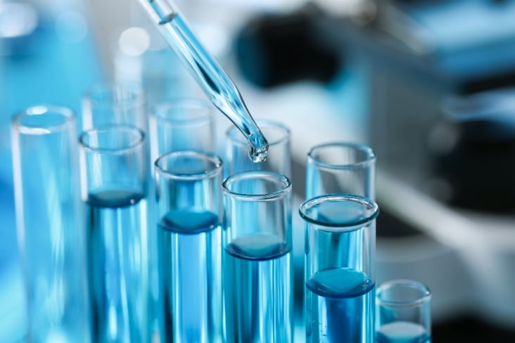 Dripping liquid from pipette into test tube in laboratory, closeup