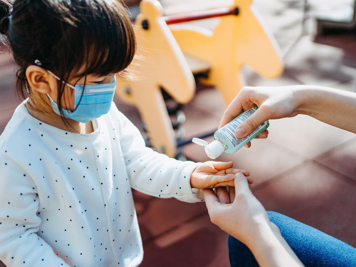 A mother squeezing hand sanitizer into child's hand