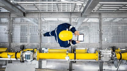 Looking down on a petroleum worker walking on a grated walkway