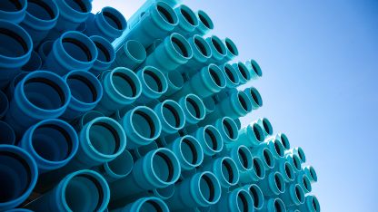 A collection of blue plastic pipes, significant for discussions on PFAS regulations and monitoring in polymer materials.