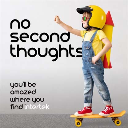 A young boy riding a skateboard while wearing a motorcycle helmet and pretend rocket strapped to his back